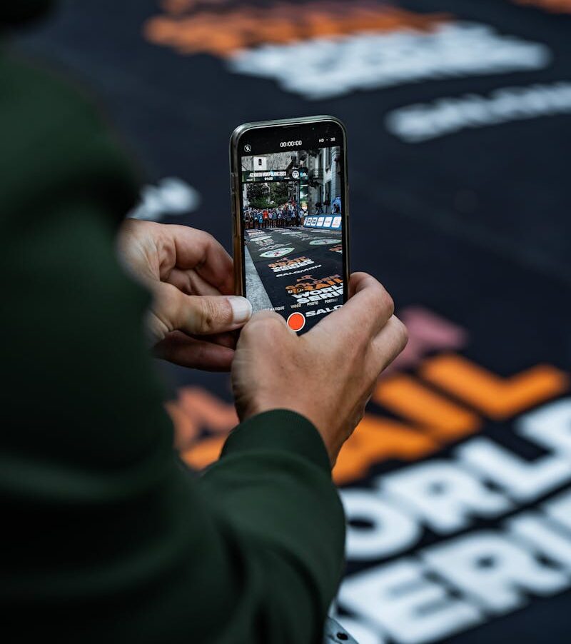 Close-up of hands holding a smartphone, filming a marathon in Chamonix.